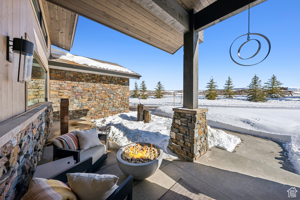 Snow covered patio featuring a patio and an outdoor living space with a fire pit