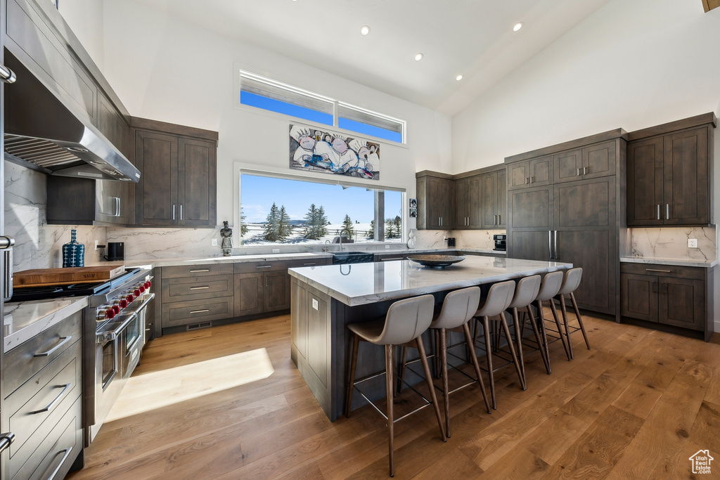Kitchen with high vaulted ceiling, range with two ovens, extractor fan, a kitchen bar, and a center island