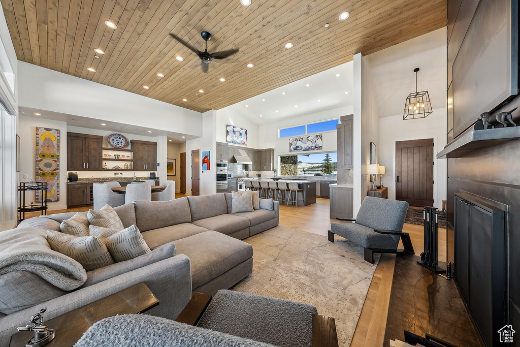 Living room featuring recessed lighting, light wood-style floors, a high ceiling, wooden ceiling, and a chandelier