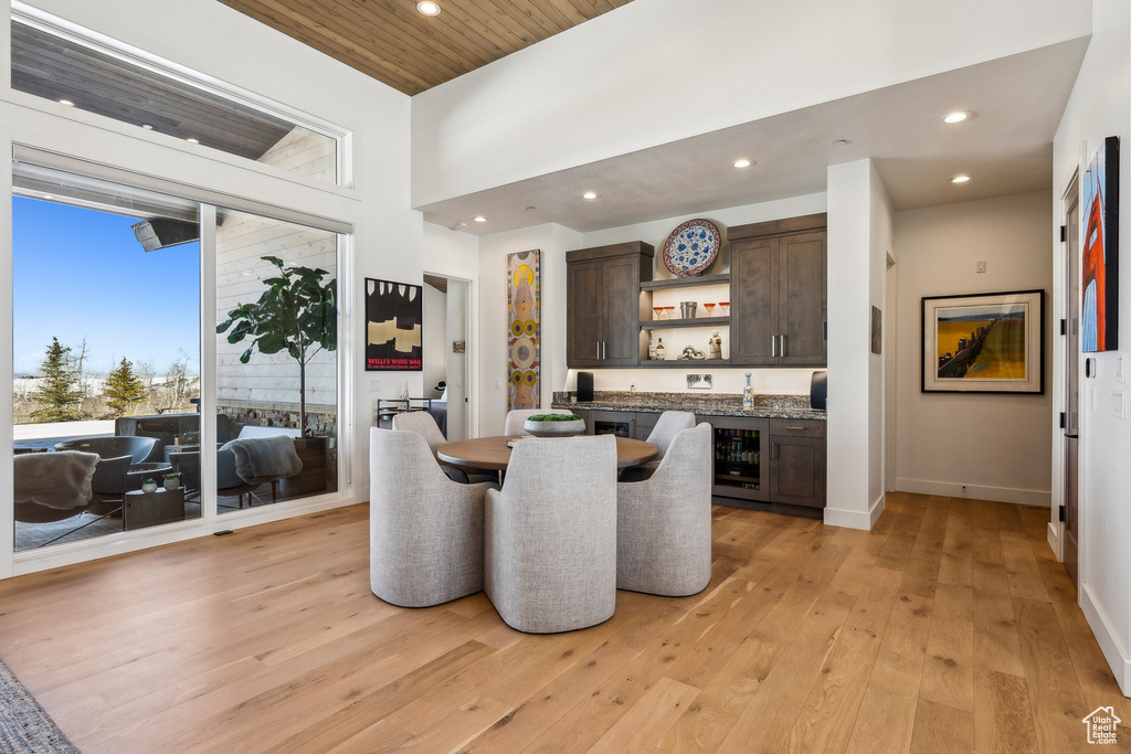 Dining room with bar with sink, light wood-style flooring, recessed lighting, wine cooler, and wooden ceiling