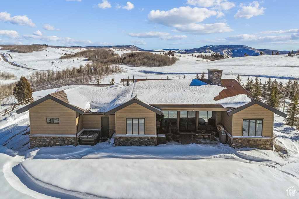 View of front of house featuring stone siding, a mountain view, and a chimney