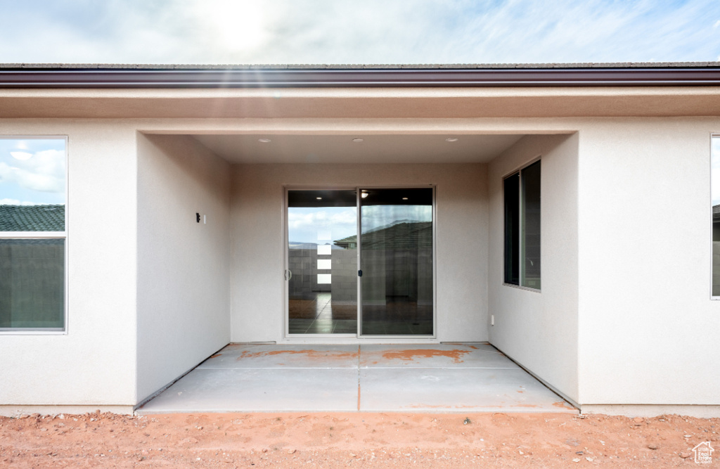 View of exterior entry with a patio and stucco siding