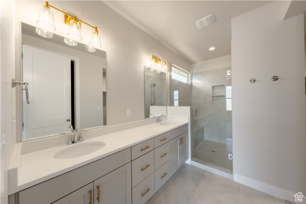 Bathroom with double vanity, tile patterned floors, a sink, and a stall shower