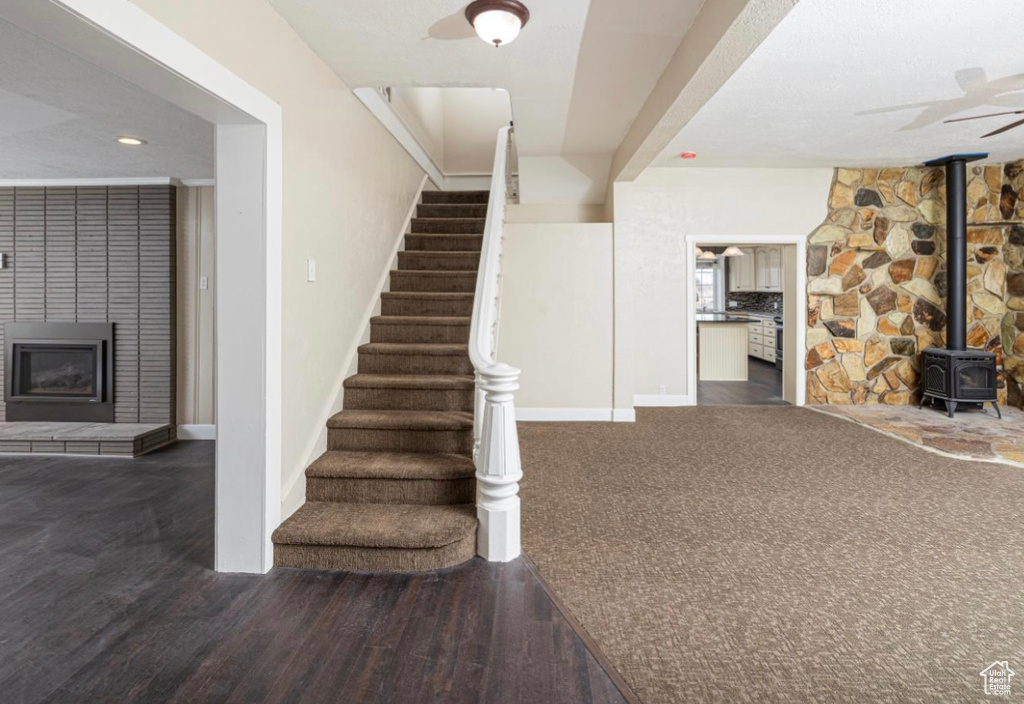 Stairs with a fireplace, wood finished floors, a wood stove, and baseboards