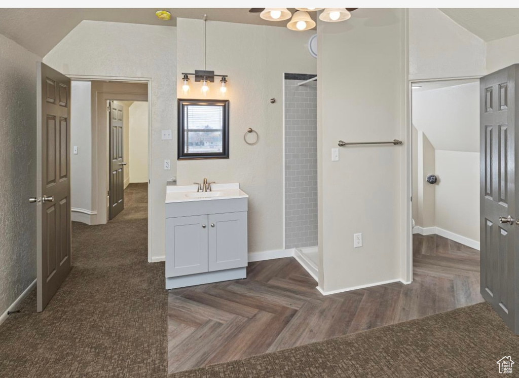 Full bathroom with tiled shower, vanity, and baseboards