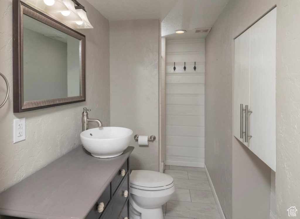 Full bathroom featuring visible vents, baseboards, a shower, toilet, and vanity