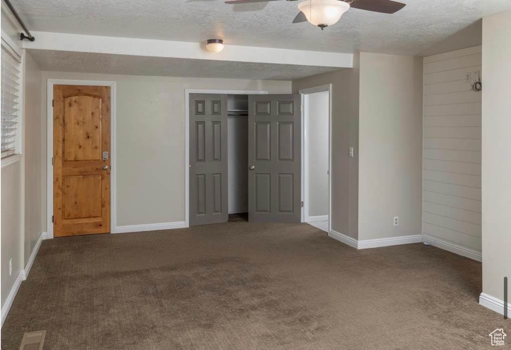 Empty room featuring carpet, visible vents, ceiling fan, and a textured ceiling