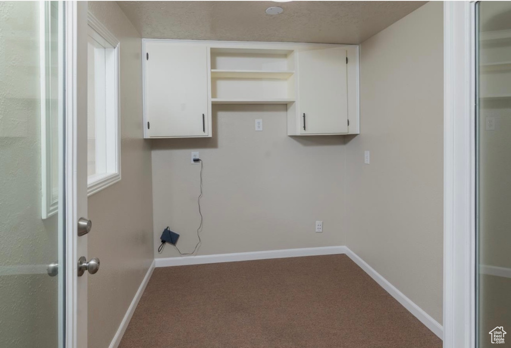 Laundry room featuring carpet and baseboards