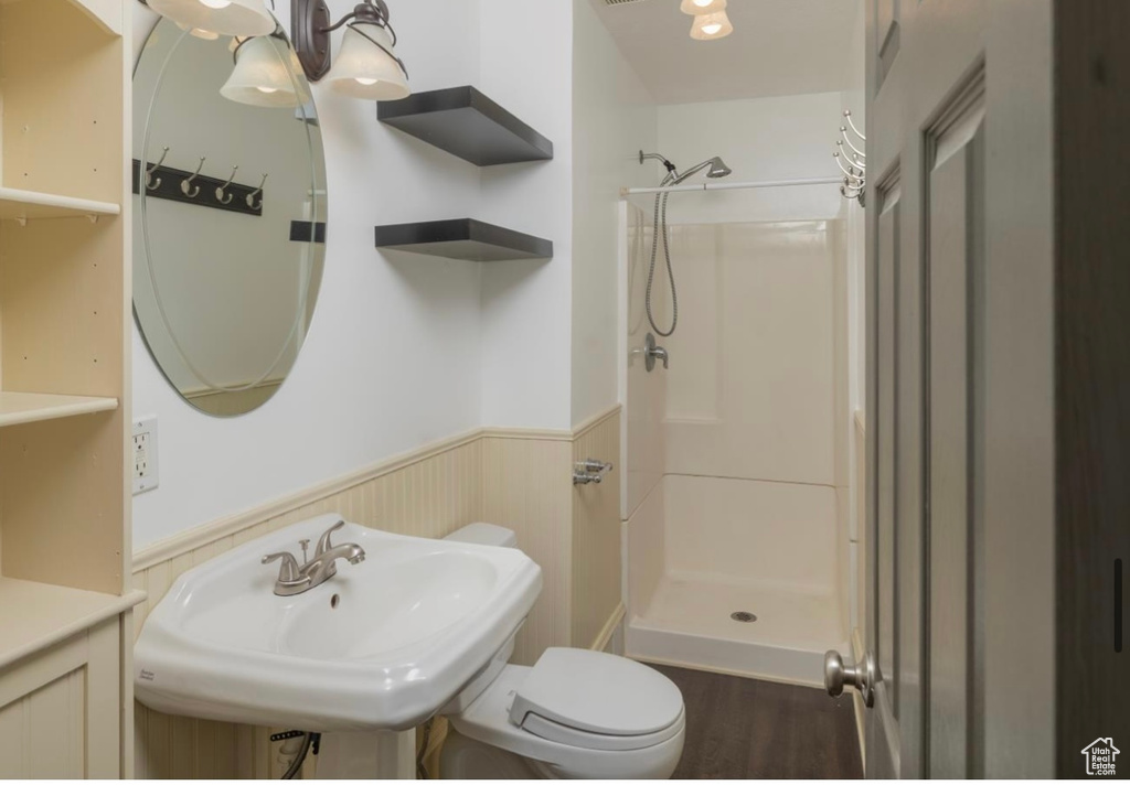 Full bath with toilet, a stall shower, wainscoting, a sink, and wood finished floors