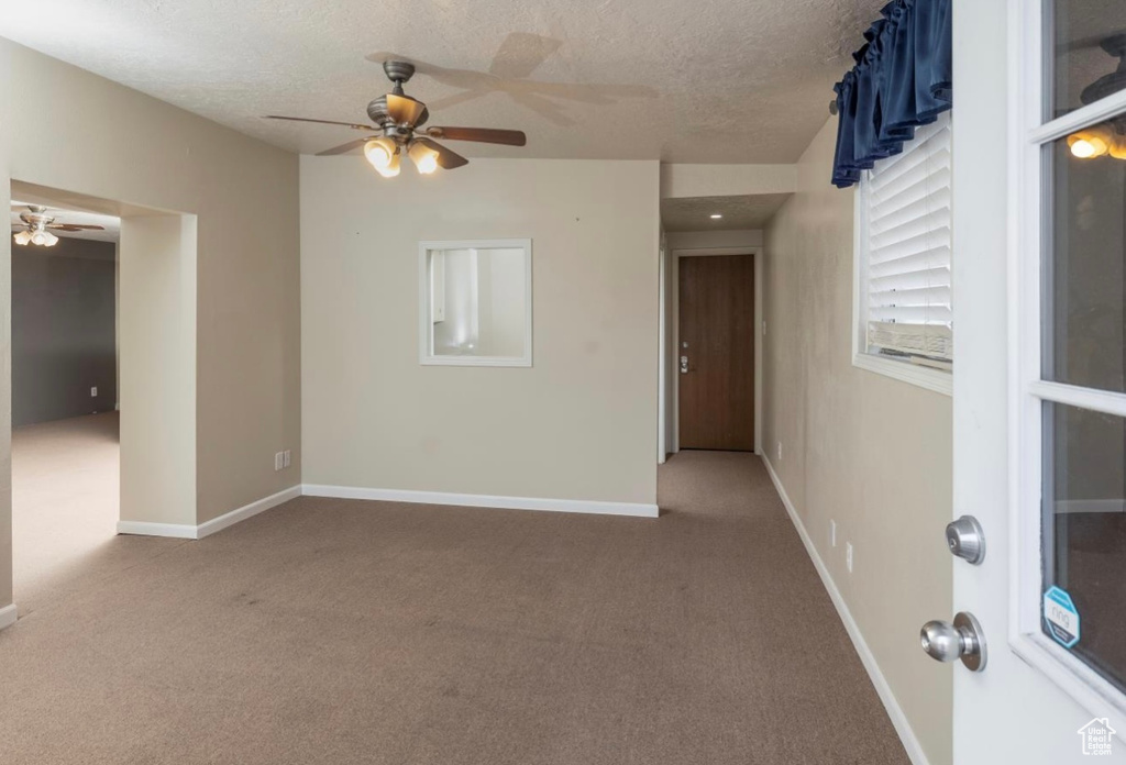 Spare room with a textured ceiling, carpet flooring, and baseboards