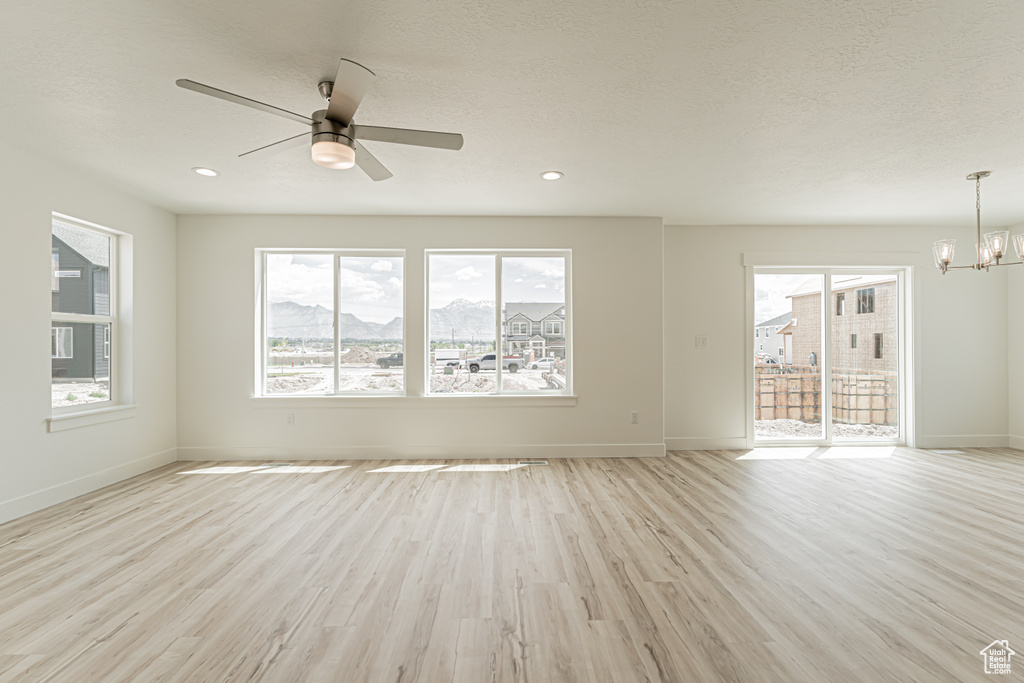 Unfurnished room with a chandelier, light wood-type flooring, ceiling fan, recessed lighting, and a textured ceiling