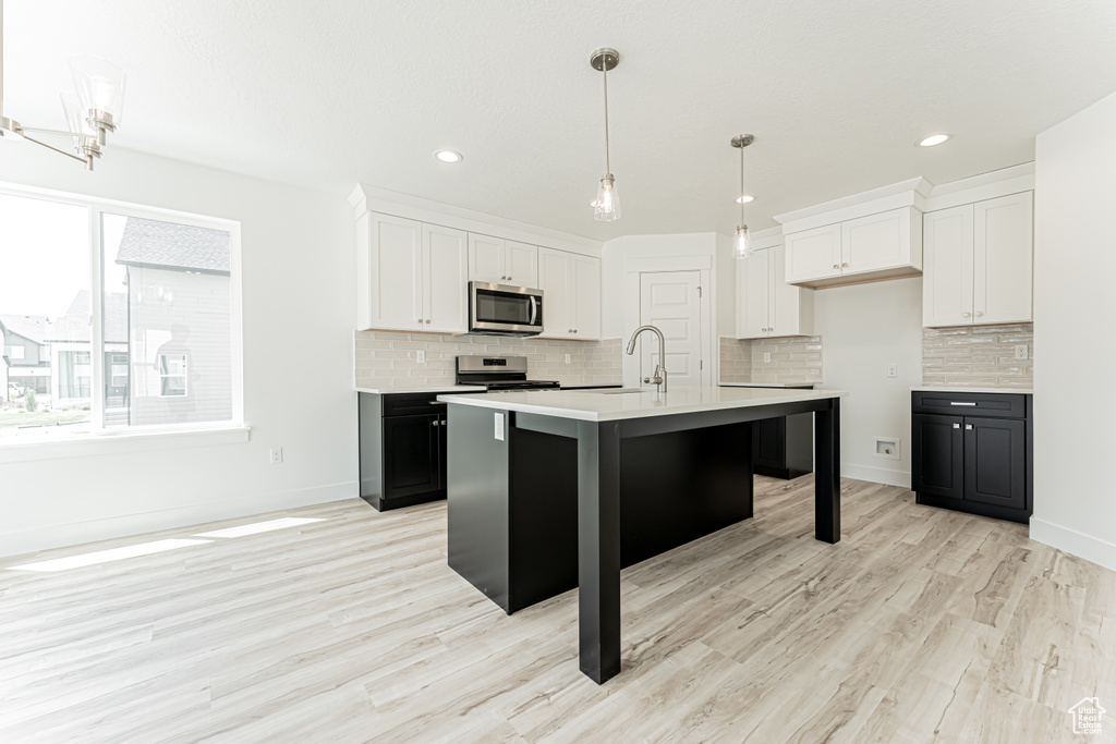 Kitchen with stainless steel appliances, light countertops, white cabinetry, tasteful backsplash, and recessed lighting