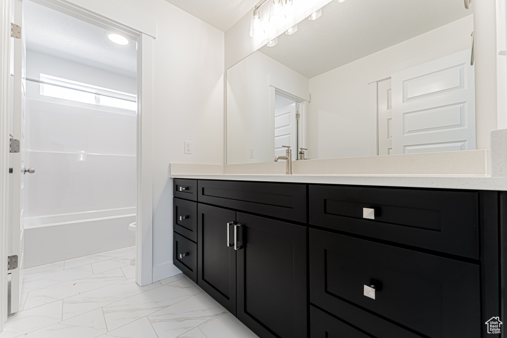 Bathroom featuring vanity, marble look tiles, and shower / bath combination