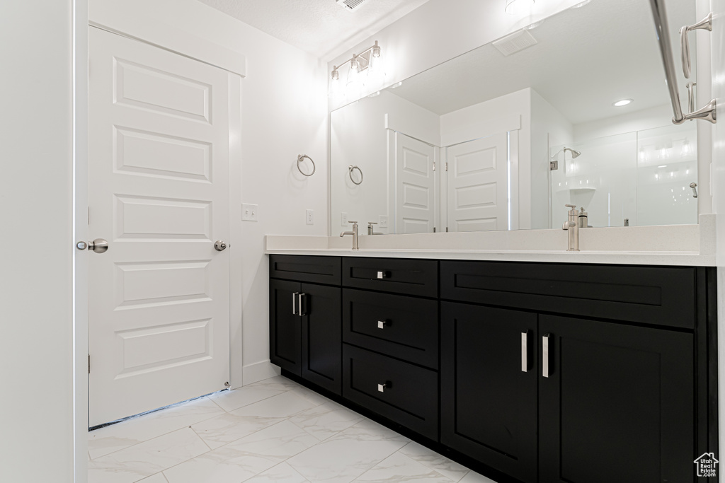 Bathroom with marble look tiles, double vanity, and a stall shower