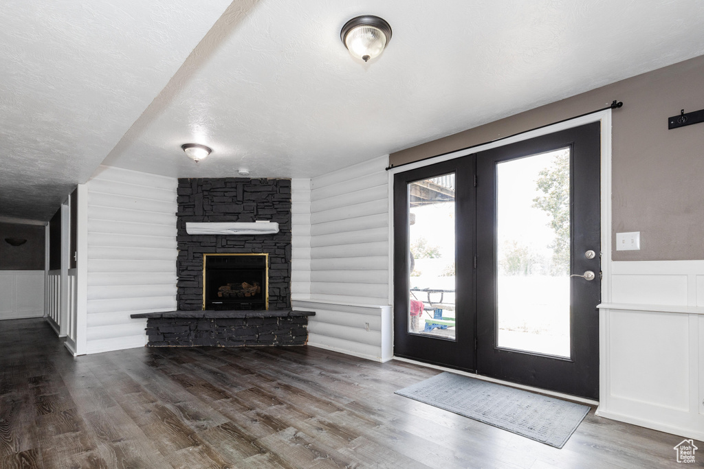 Interior space featuring log walls, a fireplace, a textured ceiling, and wood finished floors