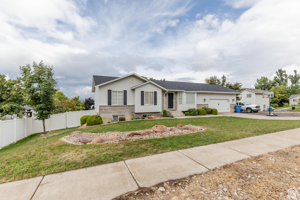 Single story home featuring an attached garage, a front yard, entry steps, fence, and driveway