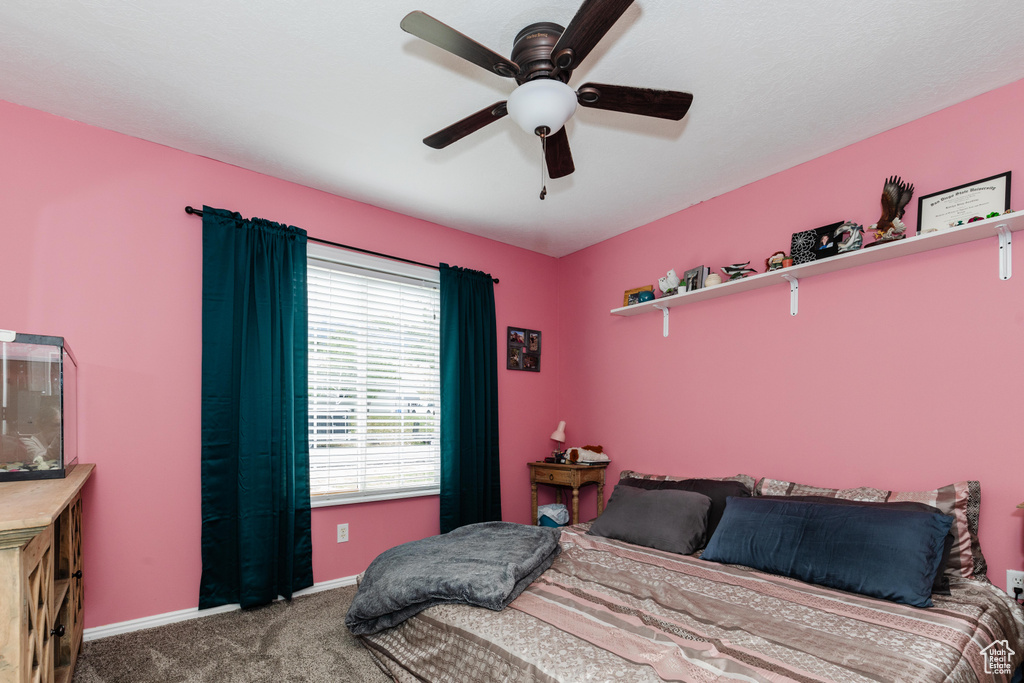 Carpeted bedroom featuring ceiling fan and baseboards