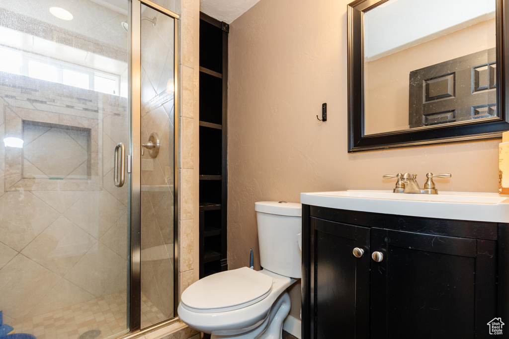 Full bathroom featuring toilet, a stall shower, and vanity