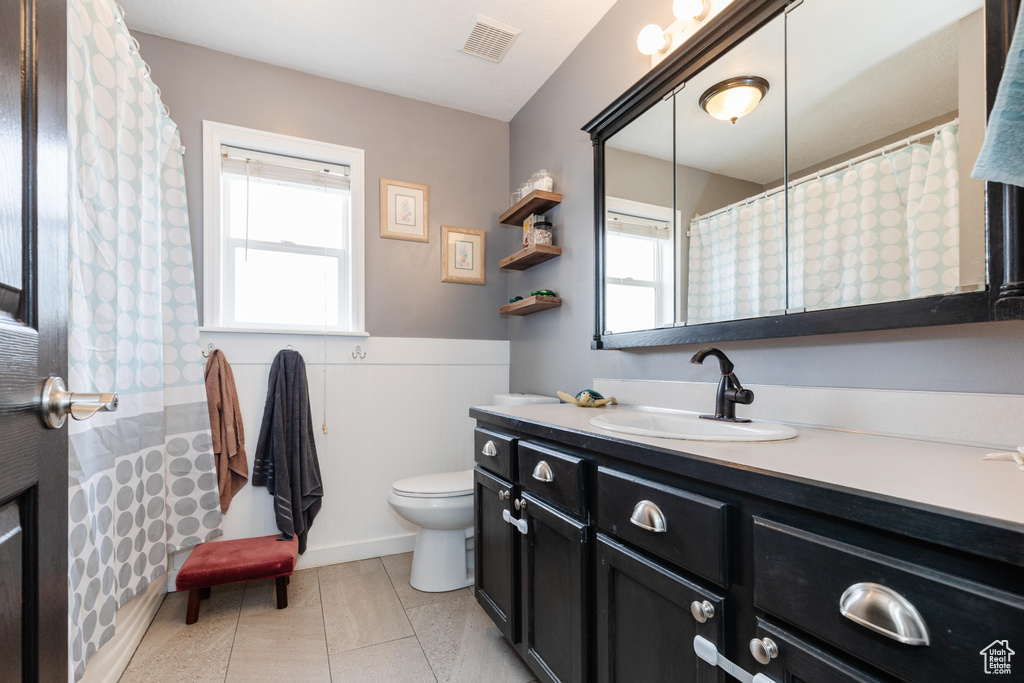 Full bath with toilet, vanity, visible vents, and tile patterned floors