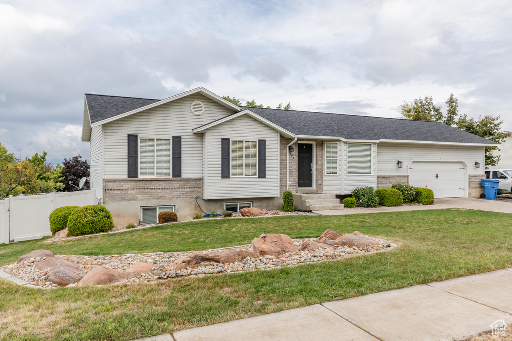 Ranch-style home with driveway, an attached garage, fence, and a front yard