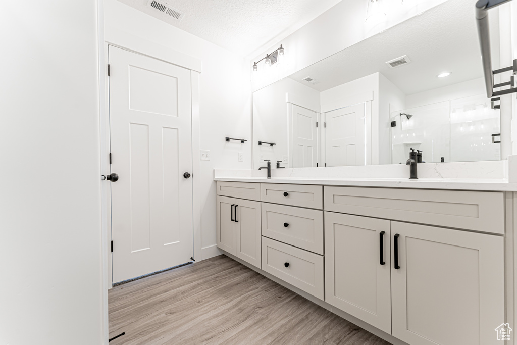 Bathroom with double vanity, a shower stall, and wood finished floors