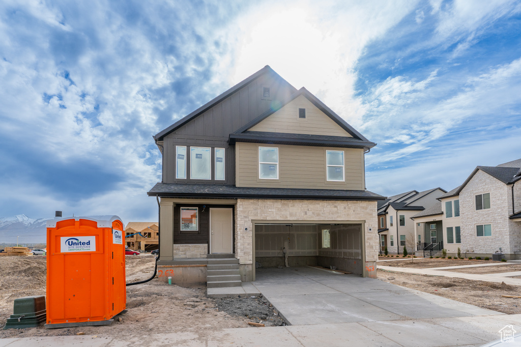 View of front of house with a garage, board and batten siding, driveway, and stone siding
