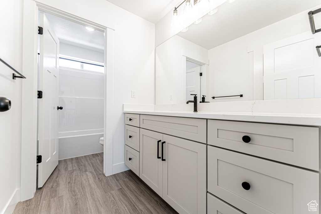 Bathroom with vanity, wood finished floors, and shower / tub combination