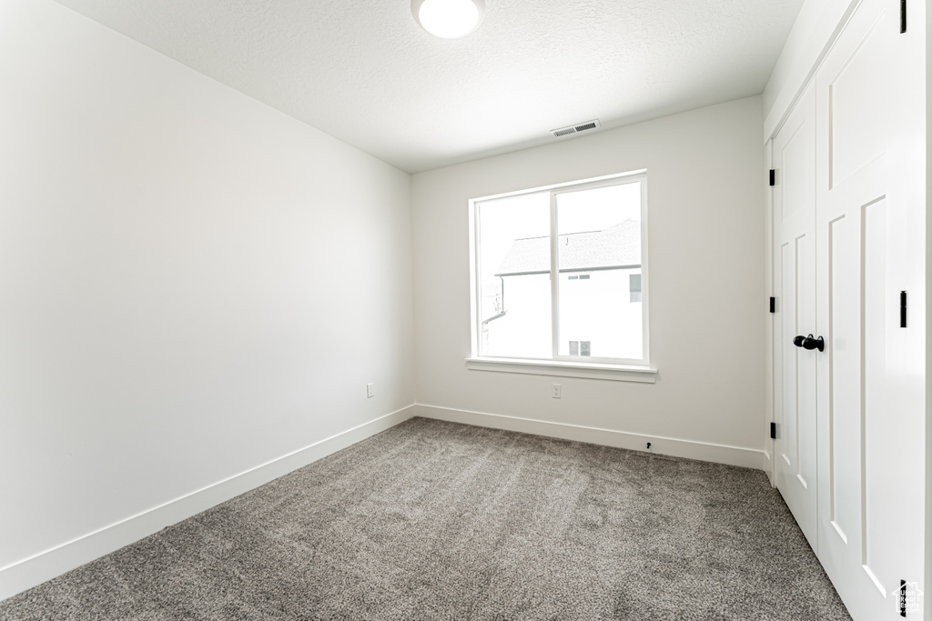 Carpeted spare room featuring baseboards
