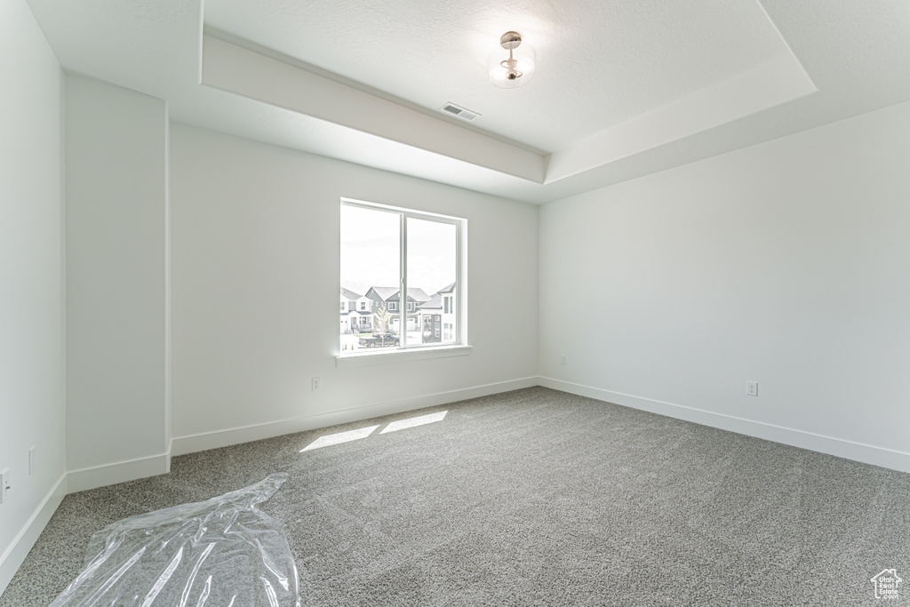 Carpeted empty room with baseboards and a tray ceiling