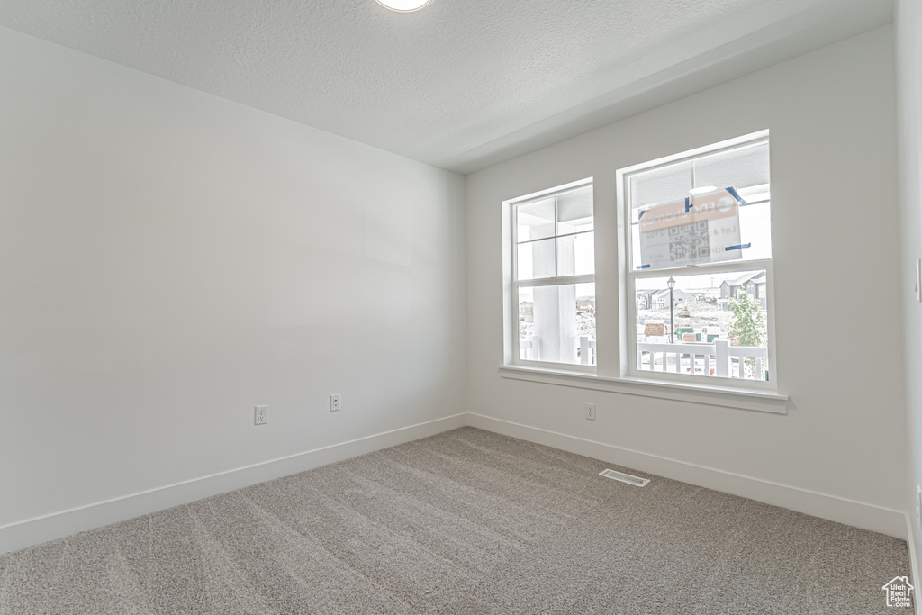 Carpeted empty room featuring baseboards and a textured ceiling
