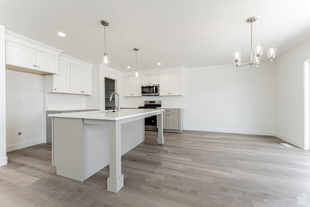 Kitchen featuring appliances with stainless steel finishes, recessed lighting, light countertops, light wood-style flooring, and a chandelier