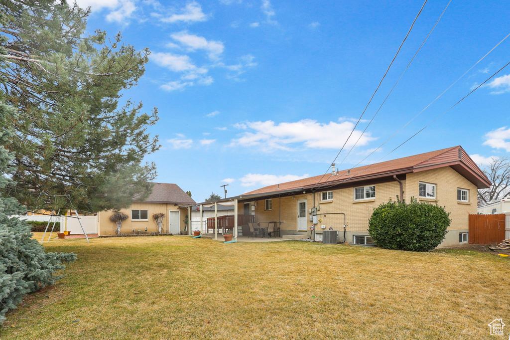 Back of house featuring a patio, brick siding, a lawn, and fence