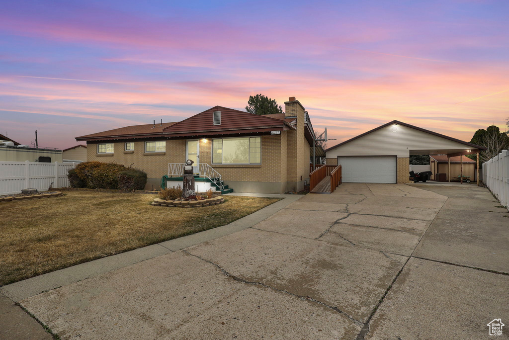 Ranch-style house featuring fence, an outdoor structure, a front yard, a carport, and brick siding