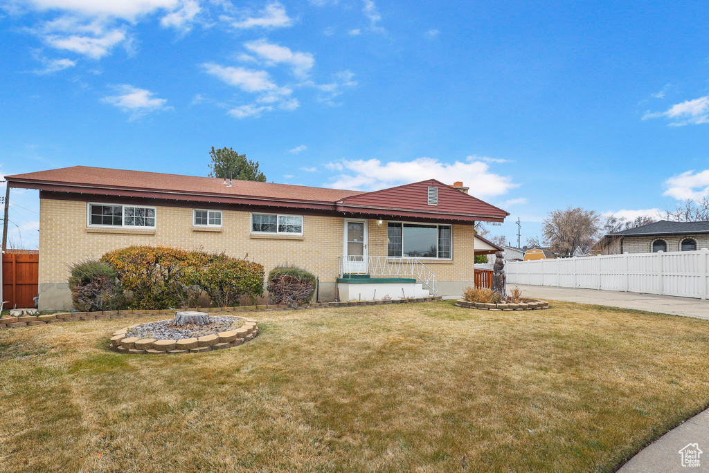 View of front facade featuring fence, a front lawn, and brick siding