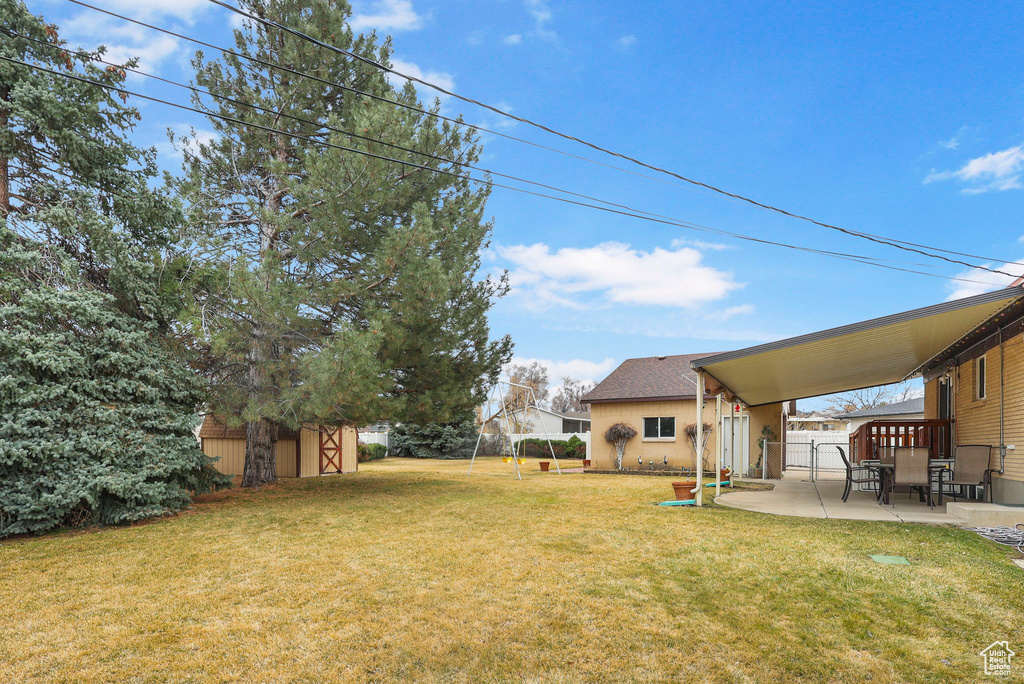 View of yard featuring a storage unit, fence, an outbuilding, and a patio