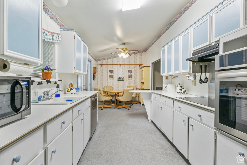 Kitchen featuring light carpet, lofted ceiling, stainless steel appliances, light countertops, and a sink