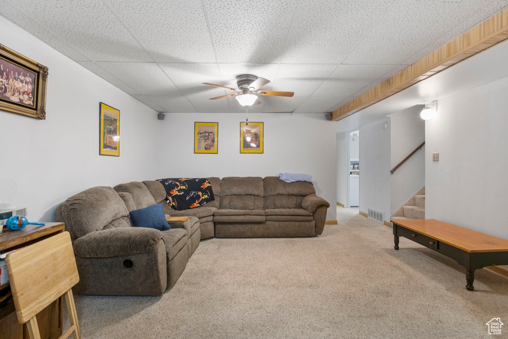 Carpeted living area with a paneled ceiling, visible vents, stairway, and ceiling fan