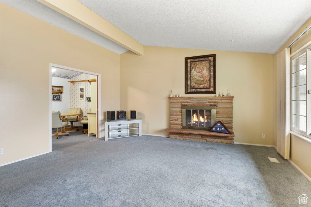 Unfurnished living room featuring vaulted ceiling with beams, a fireplace, carpet flooring, and a wealth of natural light