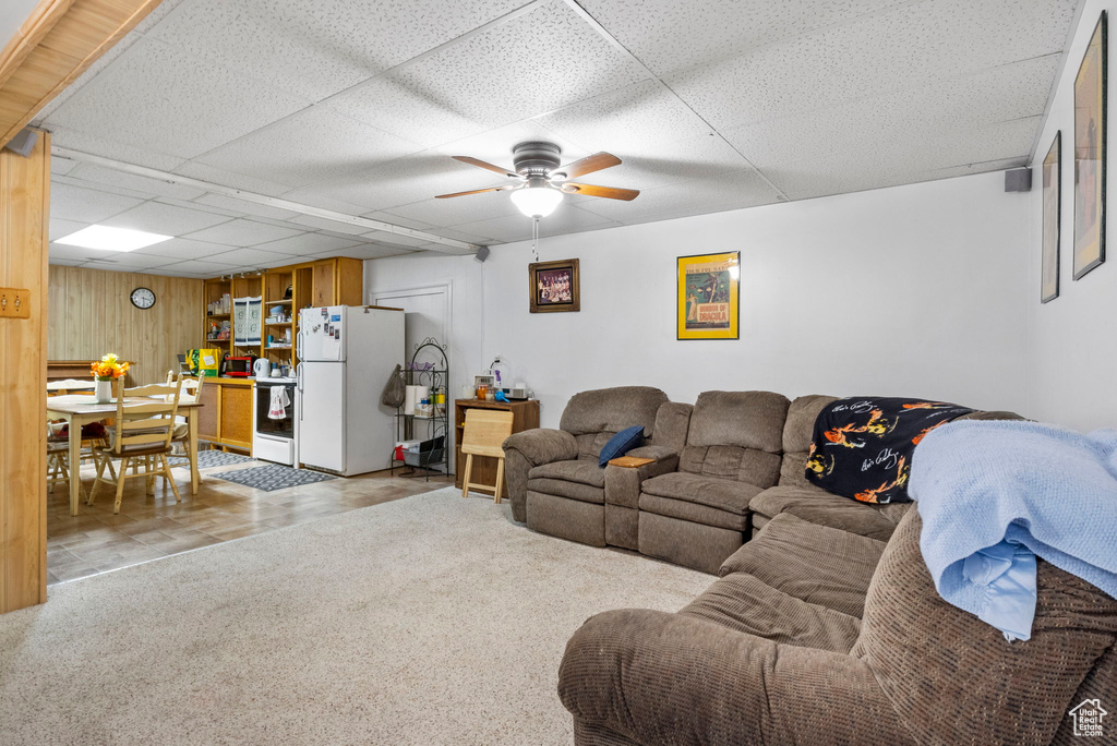 Carpeted living room featuring a ceiling fan and a drop ceiling