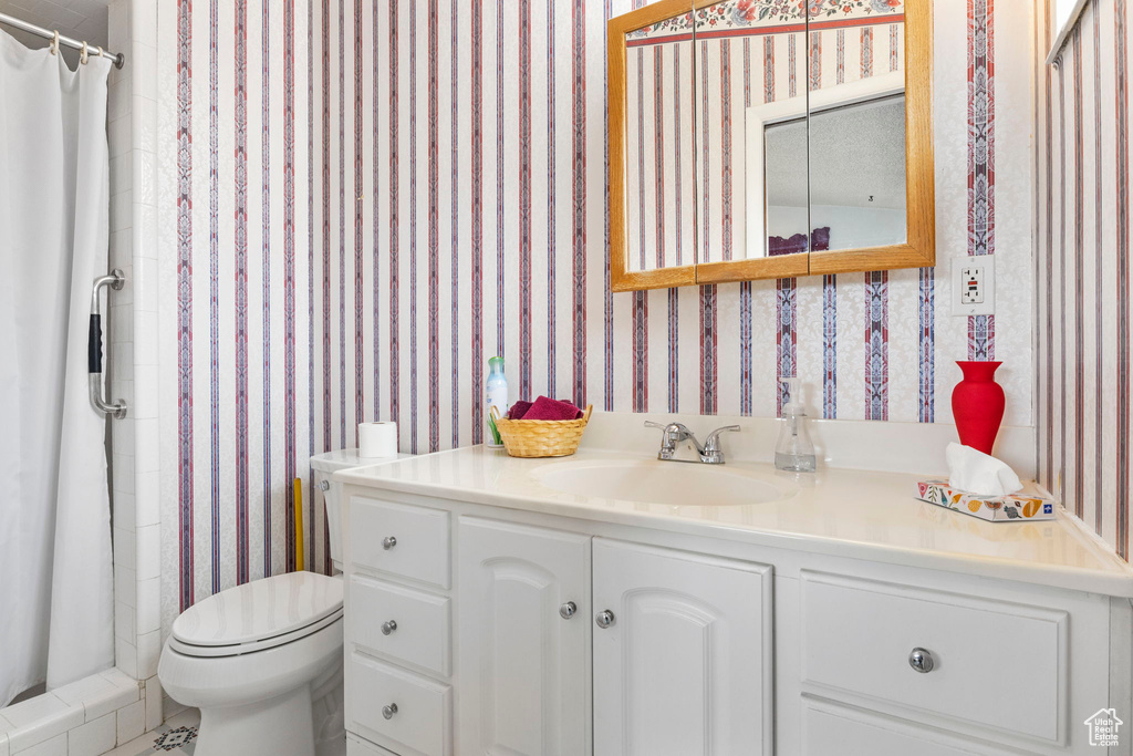 Full bath with a stall shower, vanity, toilet, and wallpapered walls