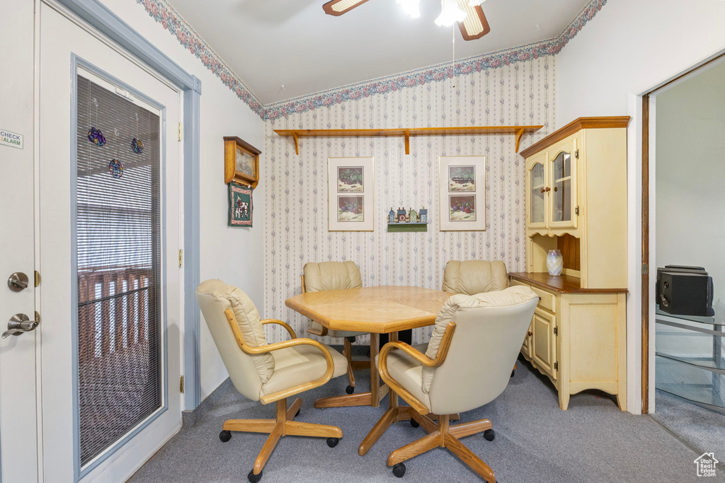 Dining space with lofted ceiling, carpet floors, a ceiling fan, and wallpapered walls