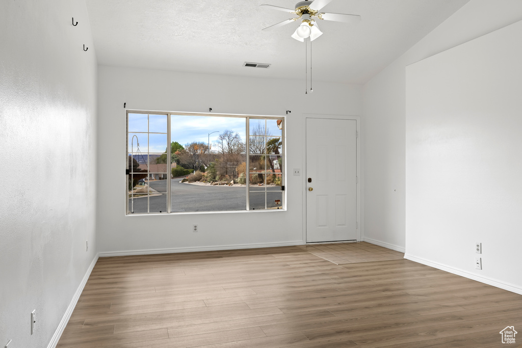 Empty room with a ceiling fan, baseboards, visible vents, and wood finished floors