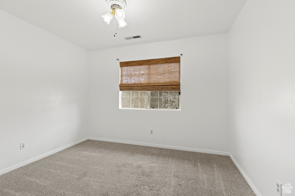 Spare room featuring a ceiling fan, carpet, visible vents, and baseboards