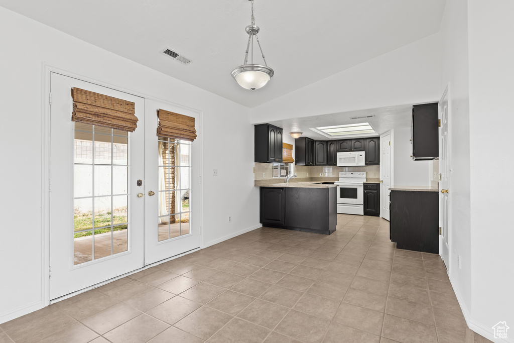 Kitchen with vaulted ceiling, light countertops, white appliances, and french doors