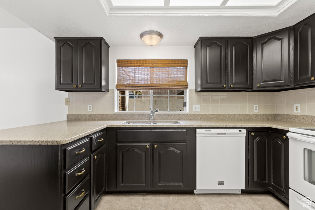 Kitchen featuring decorative backsplash, electric range oven, a sink, dishwasher, and a peninsula