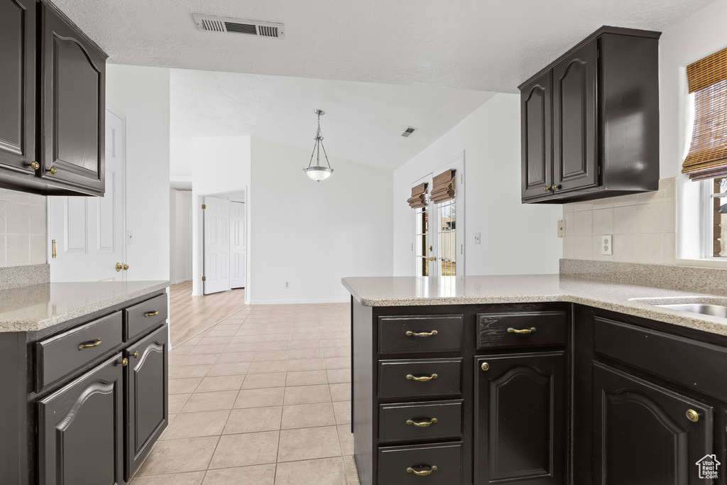 Kitchen with a peninsula, tasteful backsplash, light tile patterned flooring, and visible vents