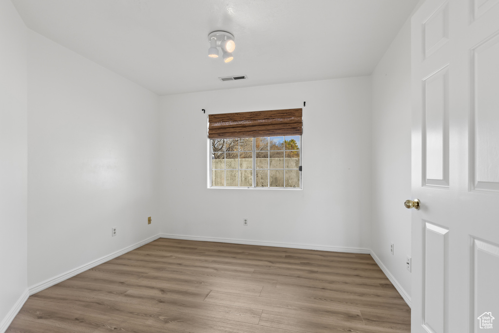 Empty room featuring visible vents, baseboards, and wood finished floors