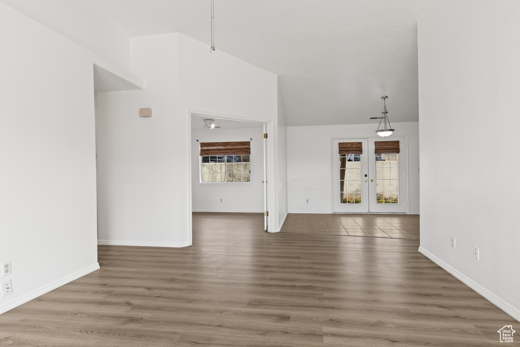 Unfurnished living room featuring high vaulted ceiling, french doors, baseboards, and wood finished floors