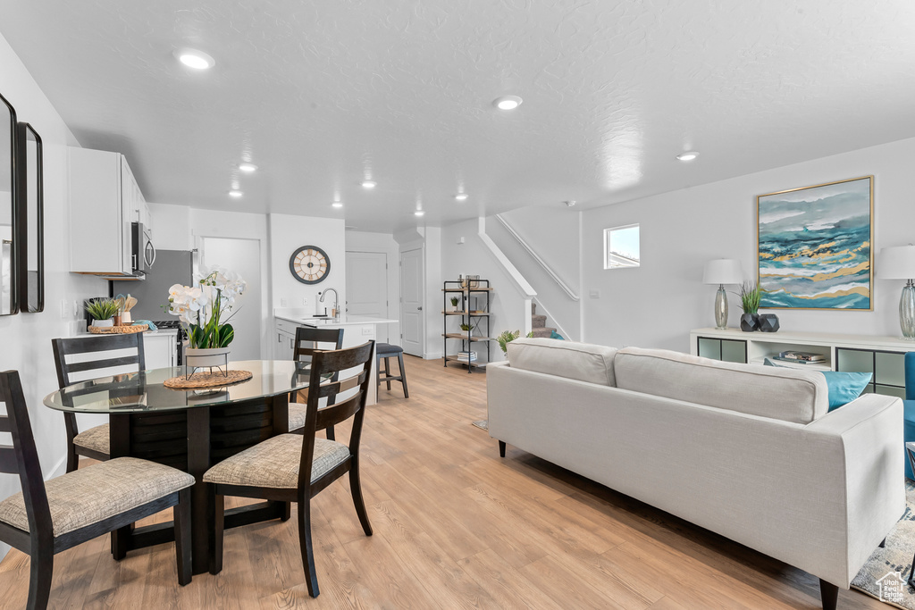 Dining area featuring a textured ceiling, stairway, light wood-style flooring, and recessed lighting