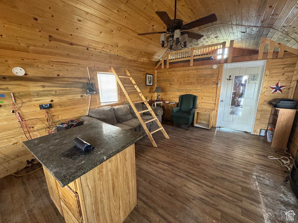 Living area featuring wood walls, lofted ceiling, dark wood finished floors, wooden ceiling, and ceiling fan